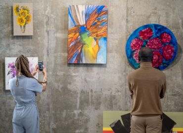 Back view of two intercultural visitors of modern art gallery