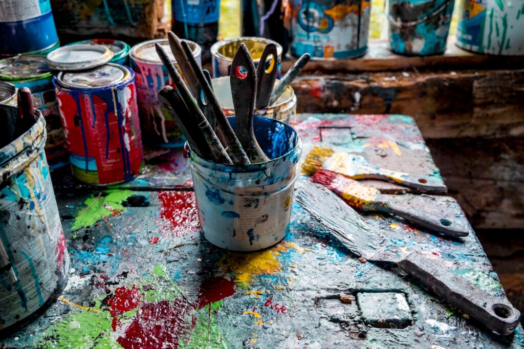 Paint brushes and pots of paints on workshop table